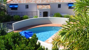 Ein zweigeschossiges Gebäude mit Ziegeldach, Swimmingpool und Meerblick.