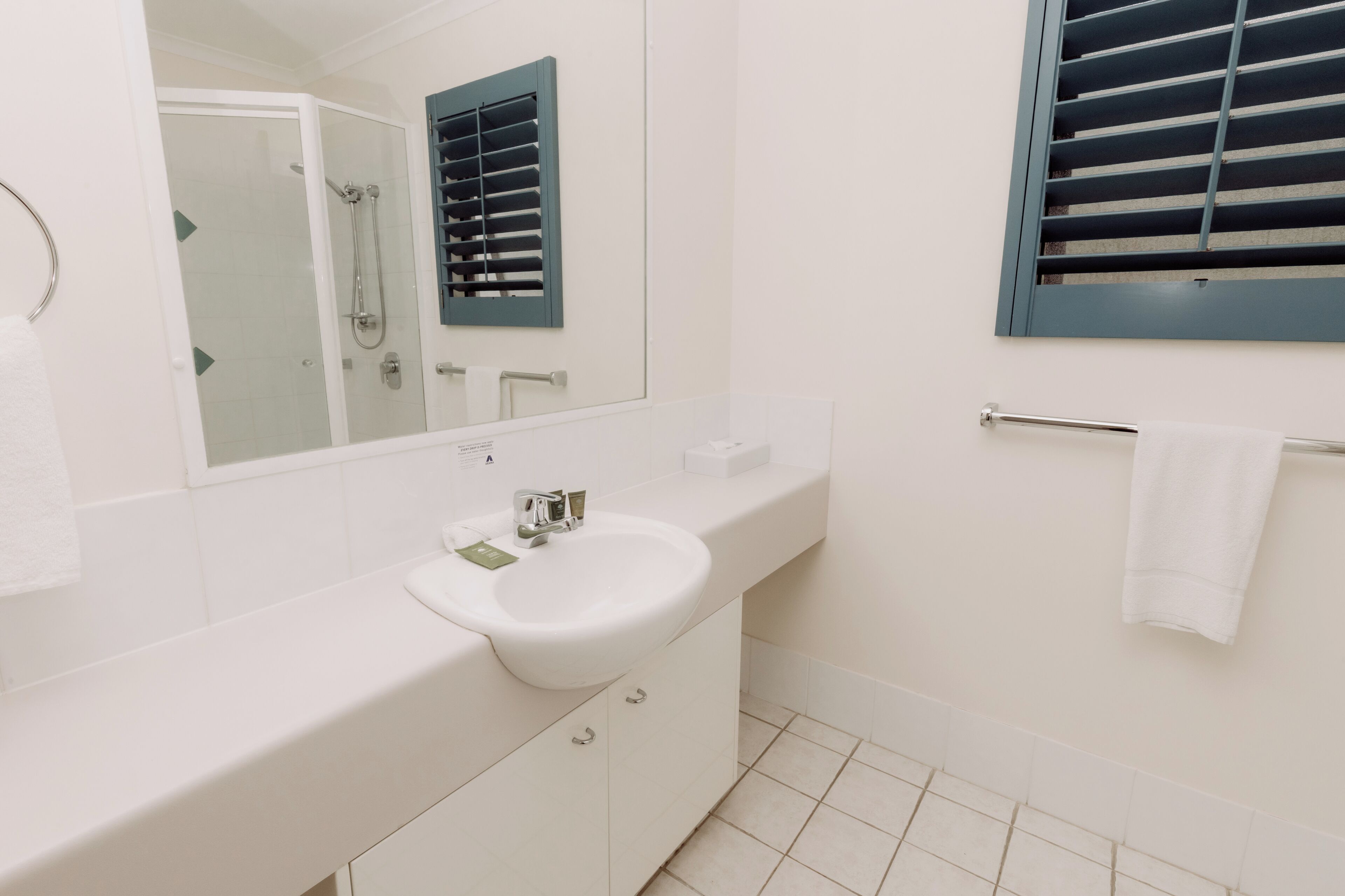 A modern bathroom with a white sink, mirror, and shower.