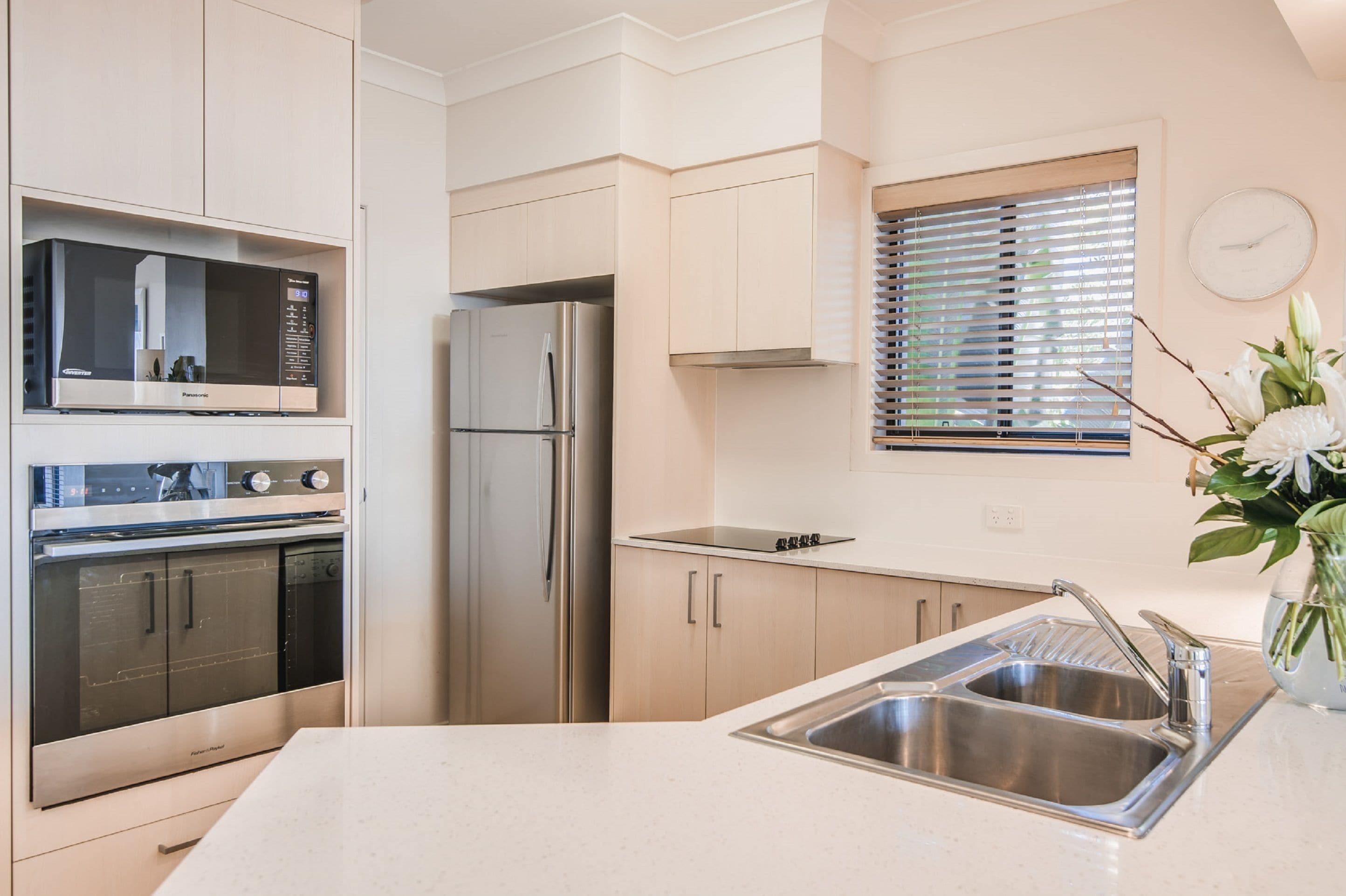 A modern kitchen with stainless steel appliances, a double sink, and light-colored cabinetry.