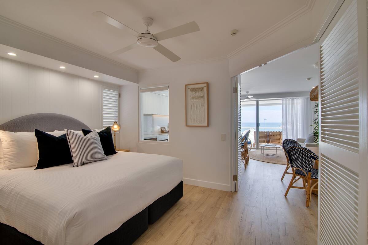 Une chambre avec un grand lit, un ventilateur de plafond et une vue sur le balcon.
