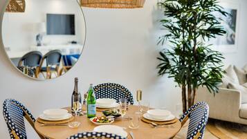 Uma mesa de jantar posta com pratos, talheres, uma garrafa de vinho e um copo de água.