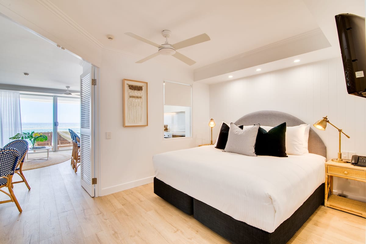 Une chambre à coucher avec un lit, une table de chevet et une vue sur l’océan, accessible par une porte coulissante.