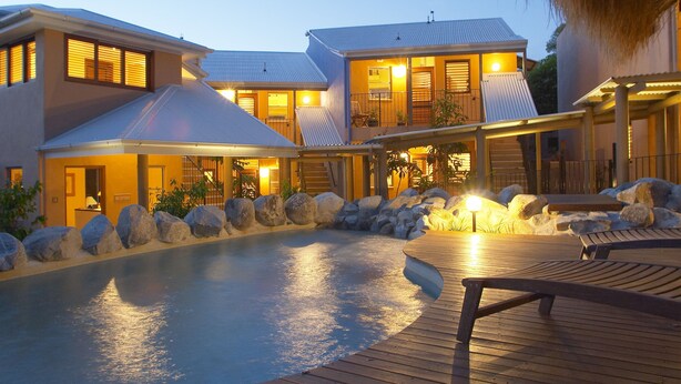 Ein modernes Resort mit Schwimmbad, Holzterrasse und mehreren Gebäuden mit großen Fenstern.