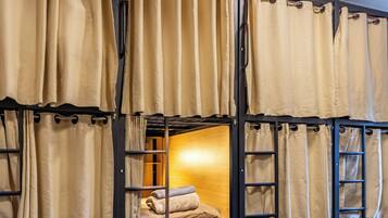 Habitación con literas, cortinas, una cama y cajones para guardar objetos.
