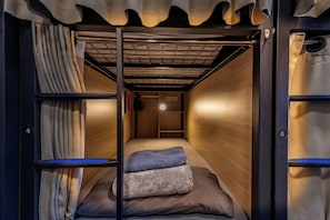 Une chambre compacte avec un lit simple et une structure de lit superposé, un petit bureau et une prise de courant.