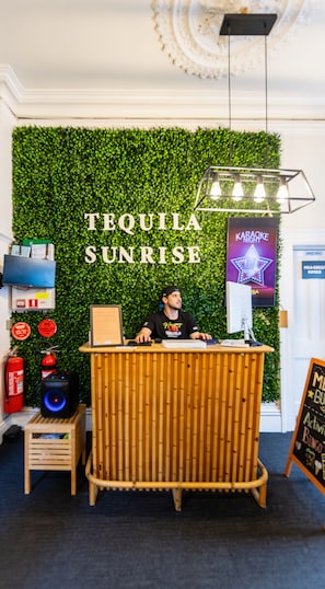 A reception desk with a green wall backdrop, a sign for 'TEQUILA SUNRISE,' and a 'KARAOKE NIGHT' poster. - Tequila Sunrise Adelaide (Adelaide)