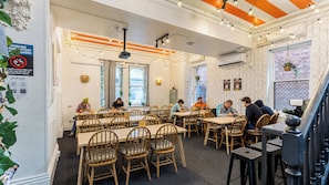 A dining area with wooden tables and chairs, a staircase, and a wall with a geometric pattern. - Tequila Sunrise Adelaide (Adelaide)