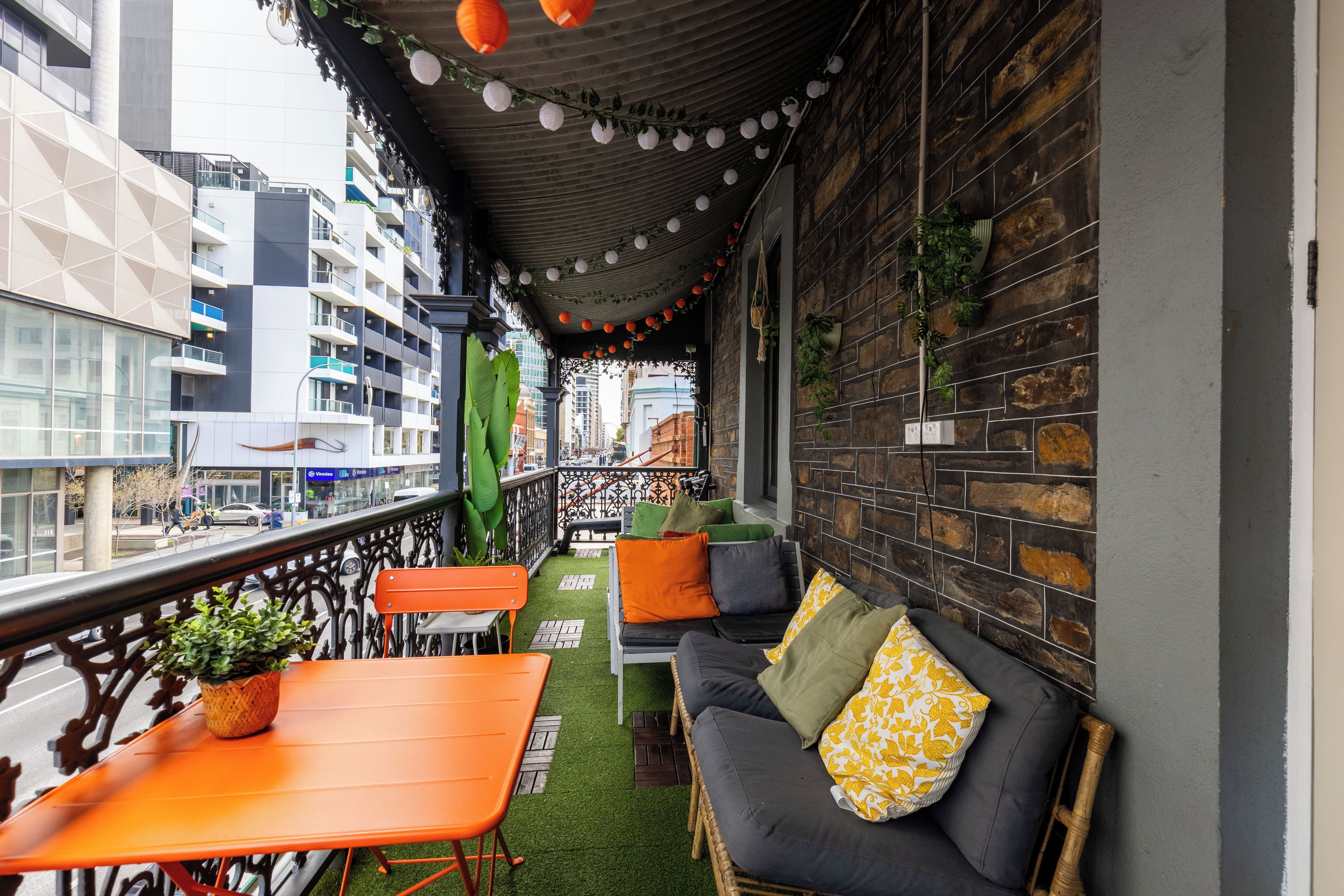 Un balcón con sofá, sillas y una mesa, con vistas a un paisaje urbano.