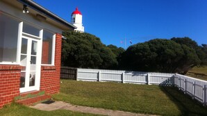 A house with a red brick exterior, a white window, and a white picket fence. - Cape Schanck Lighthouse (Boneo)