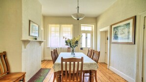 A dining room with a wooden table, chairs, a vase with flowers, and framed pictures on the walls. - Cape Schanck Lighthouse (Boneo)