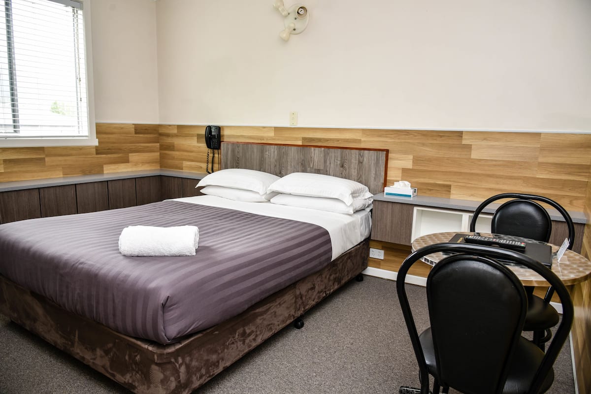 Ein Hotelzimmer mit Bett, Schreibtisch und Stuhl.