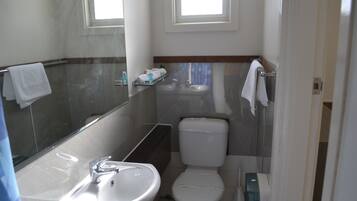 A compact bathroom with a sink, toilet, and a mirror.