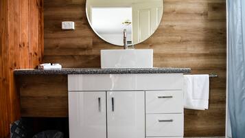 Une salle de bain avec un mur en bois, un lavabo blanc, un miroir et un porte-serviettes.