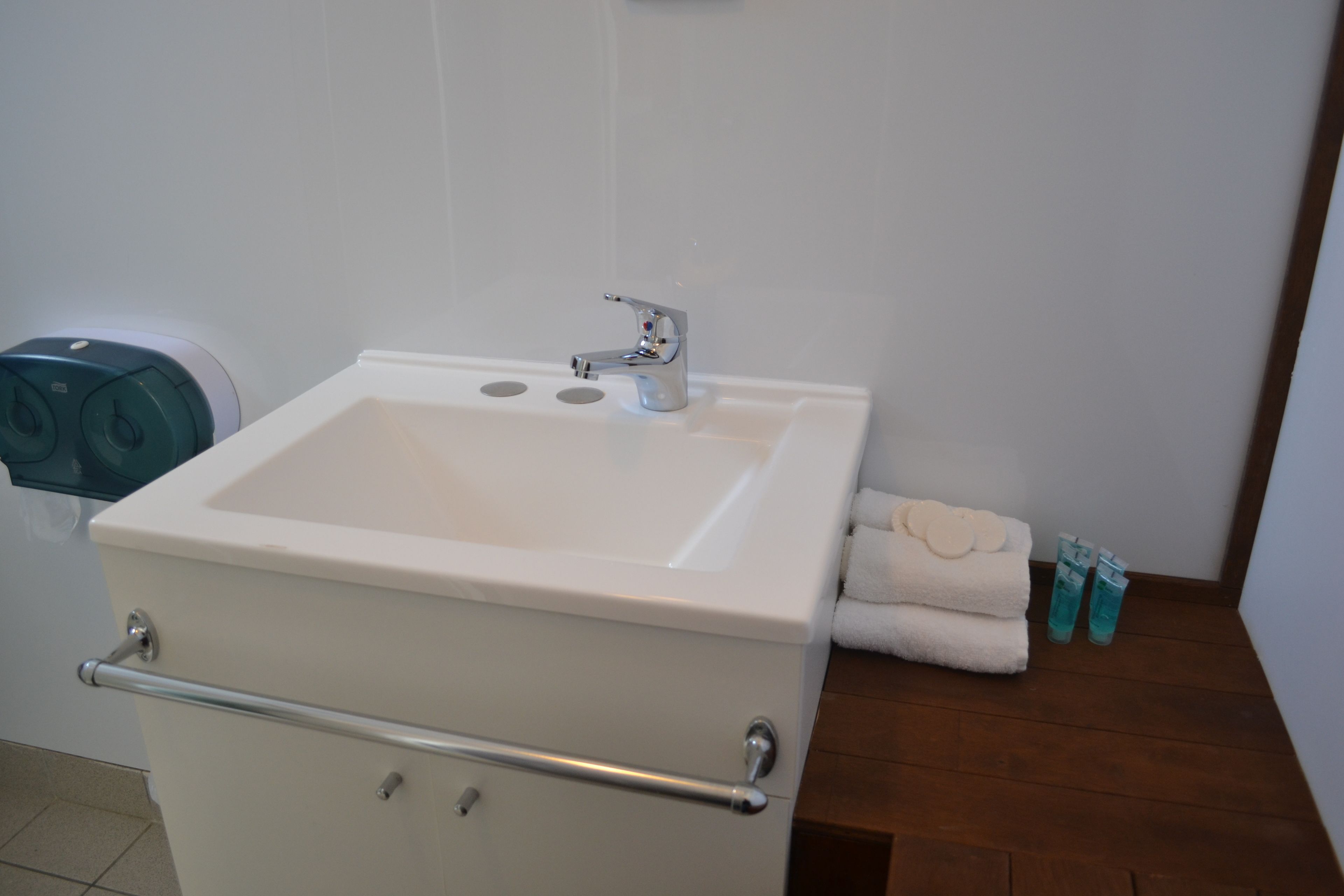 Um banheiro com pia branca, porta-toalhas e vaso sanitário.