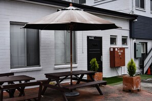 Un área de patio al aire libre con mesas de picnic y un paraguas grande.