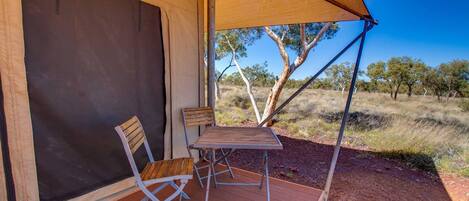 A tent with a table and two chairs on a wooden deck.