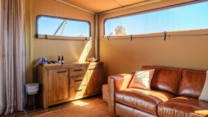 A cozy interior with a leather sofa, wooden cabinet, and a window with a view. - Karijini Eco Retreat (Karijini)