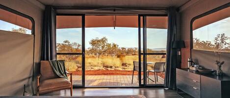 A room with a bed, a chair, a desk, and a view of the outdoors.