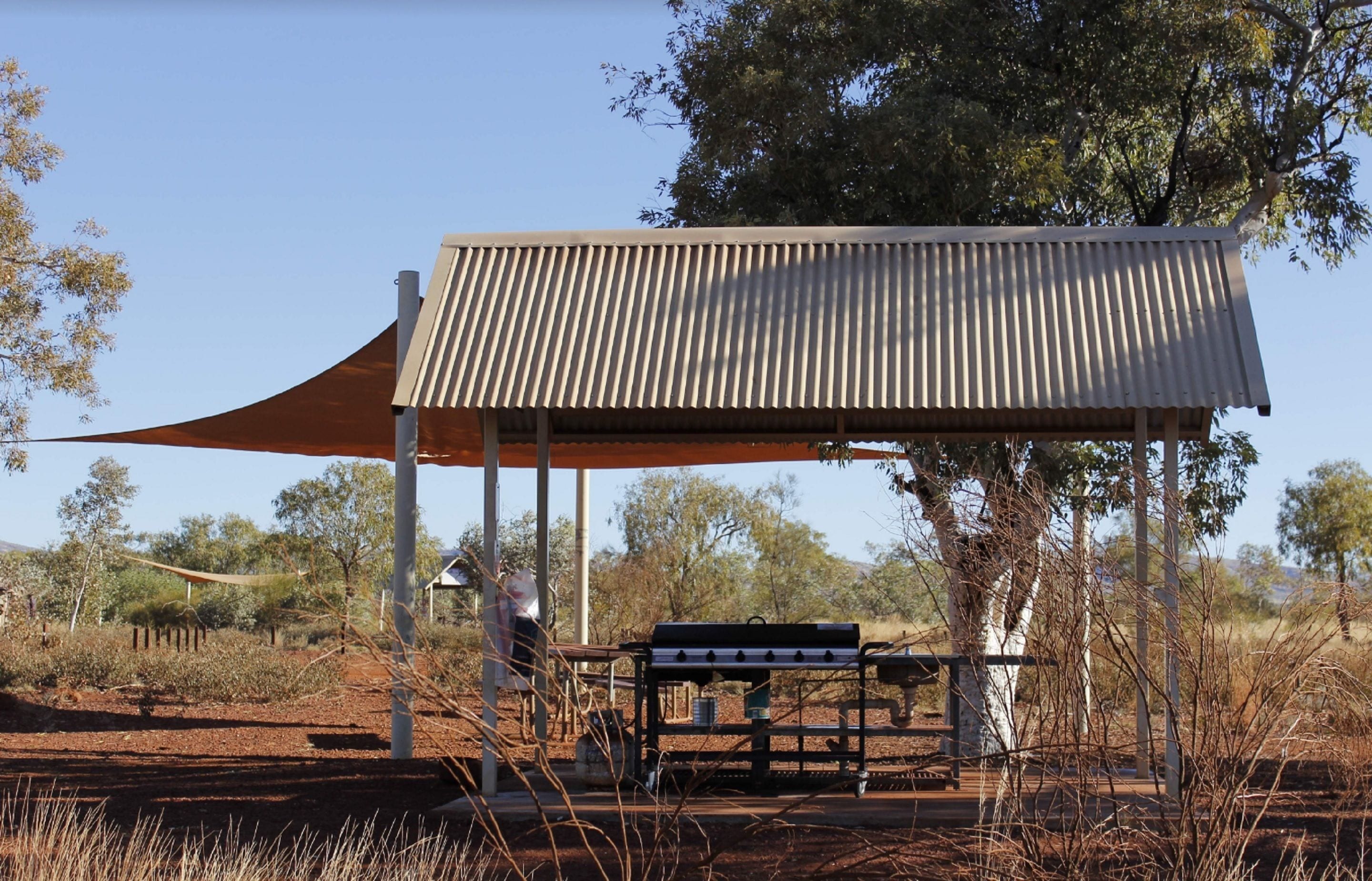 A covered outdoor seating area with a metal roof and a bench.