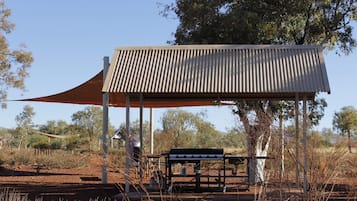 A covered outdoor seating area with a metal roof and a bench.