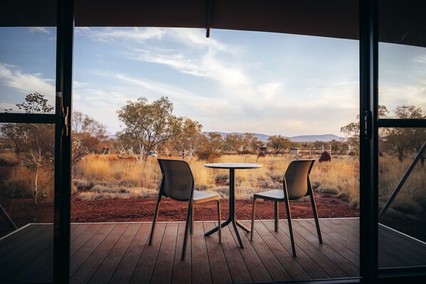 An outdoor seating area with two chairs and a table, overlooking a natural landscape with trees and distant hills. - Karijini Eco Retreat (Karijini)