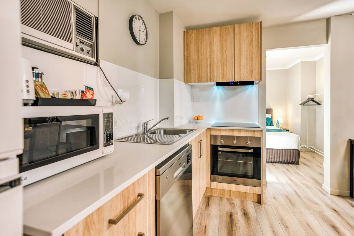 Une cuisine moderne équipée d’un four à micro-ondes, d’un four, d’un évier et de meubles de rangement en bois.