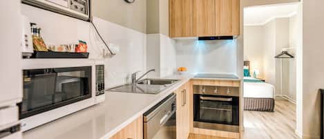 Una cocina moderna con microondas, horno, fregadero y armarios de madera.