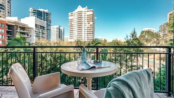A balcony with a round table and chairs, a magazine, and a bottle.