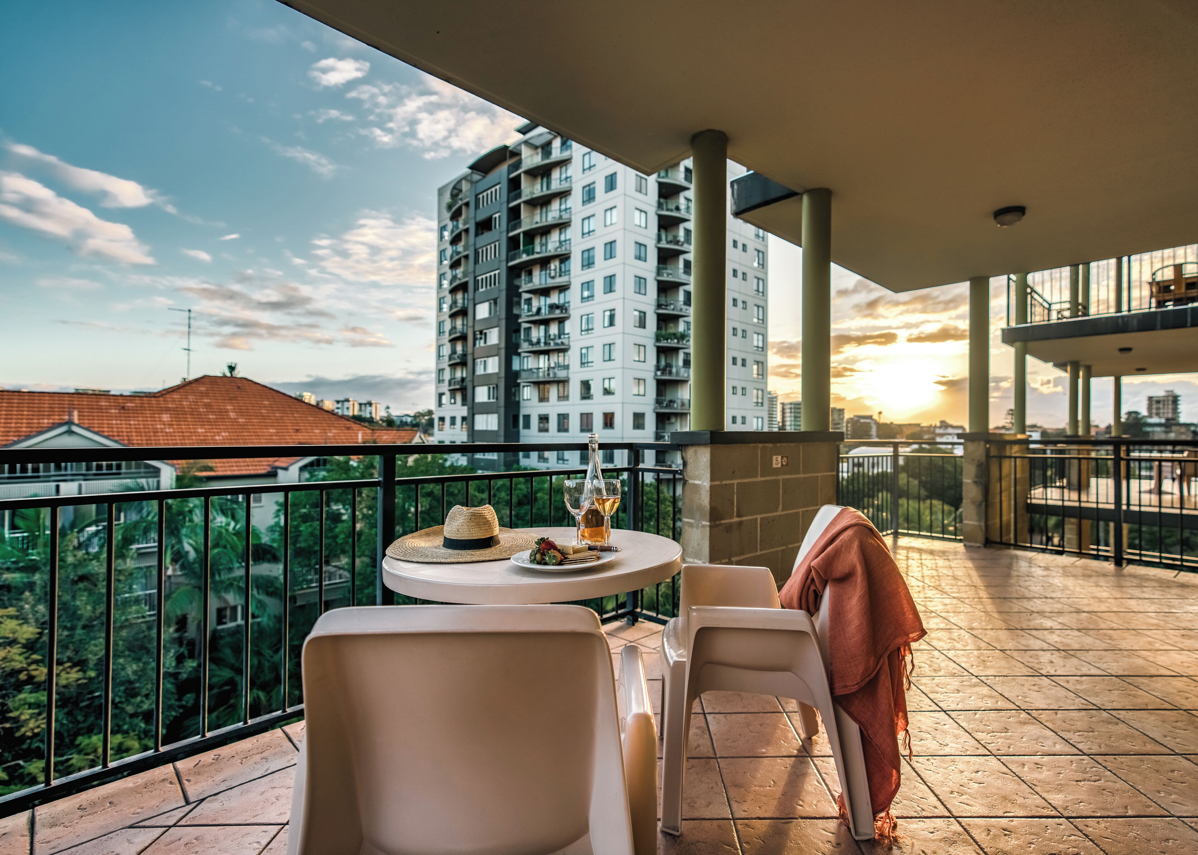 A balcony with a round table, two chairs, a bottle, and a glass of wine.
