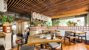 Een restaurantinterieur met houten vloeren, traditionele Japanse decoratie en uitzicht op het omliggende landschap.