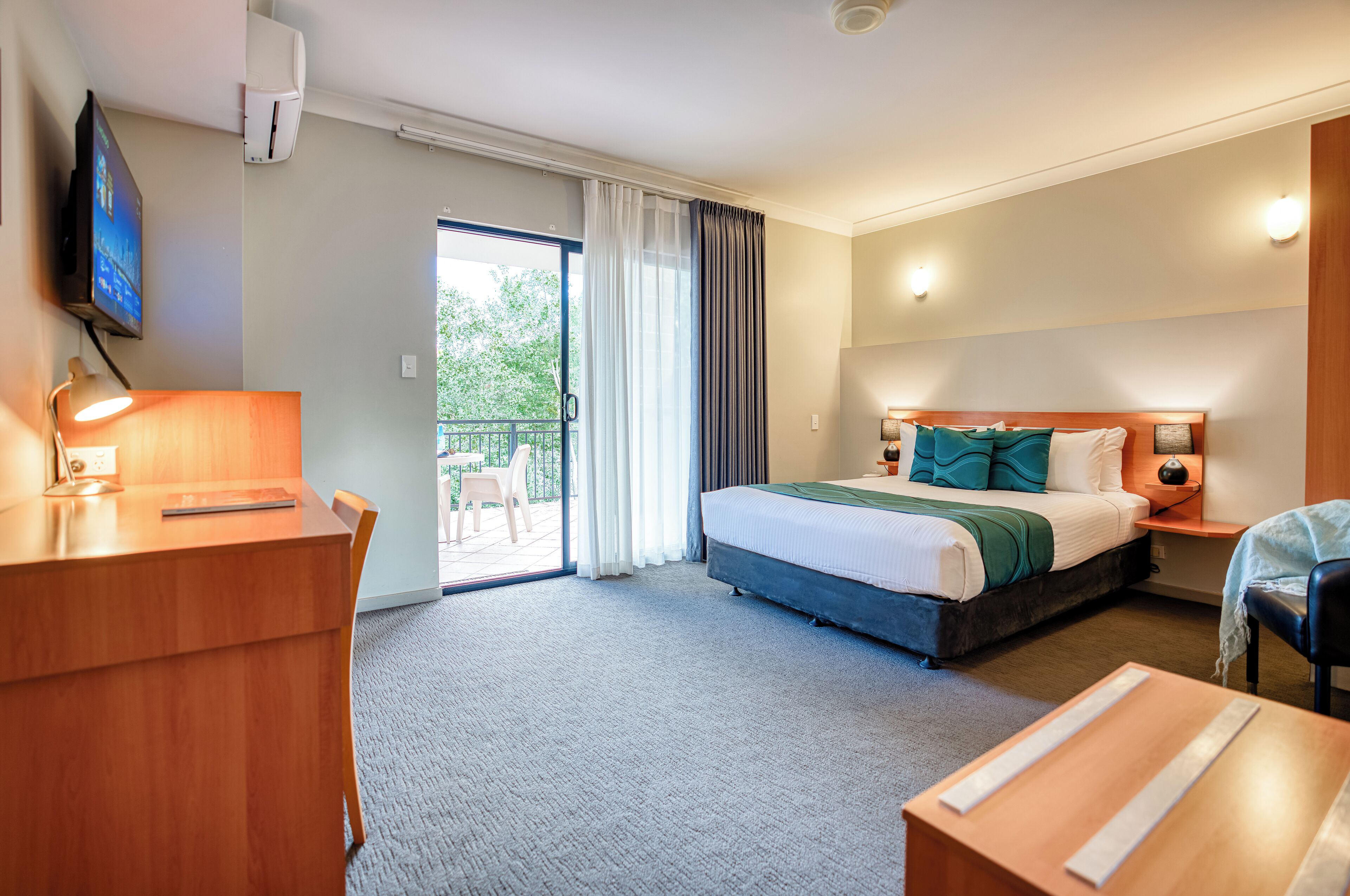 Ein Hotelzimmer mit Bett, Schreibtisch, Stuhl und Fernseher.