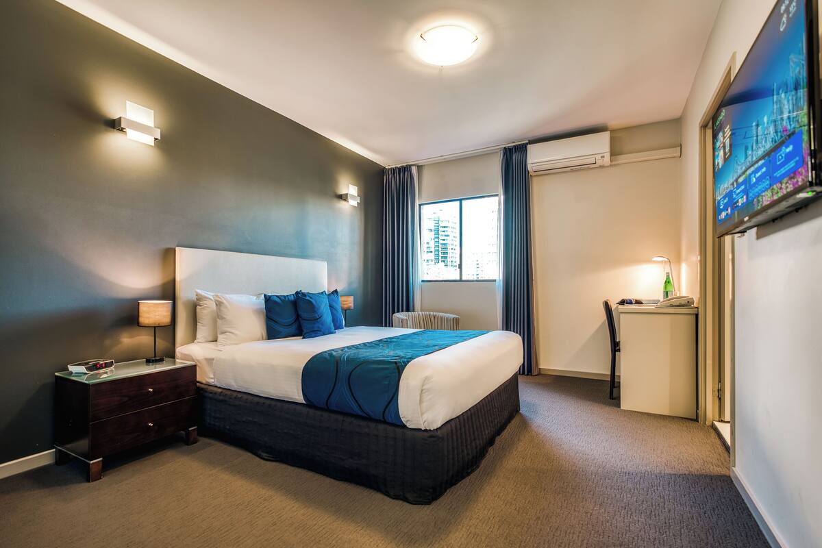 Une chambre d’hôtel avec un grand lit, des tables de chevet, un bureau et une télévision.