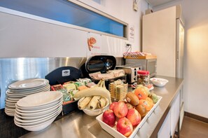 Une table de buffet avec des assiettes, des bols et des fruits, comme des pommes et des bananes.
