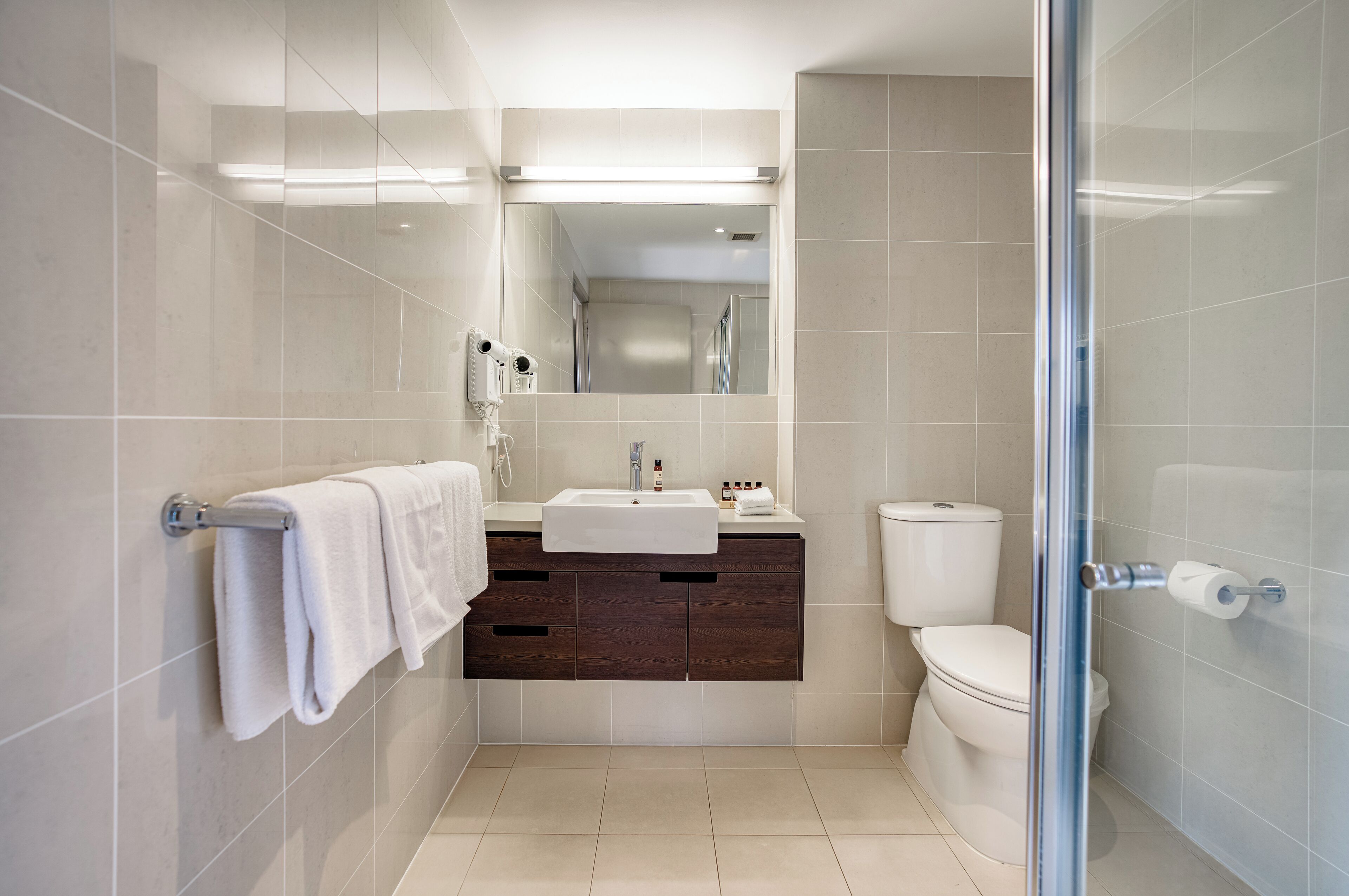 A modern bathroom with a glass shower enclosure, a white sink, and a toilet.