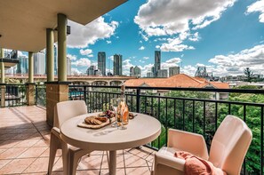 Un balcon avec une table ronde, deux chaises et un plateau de nourriture.