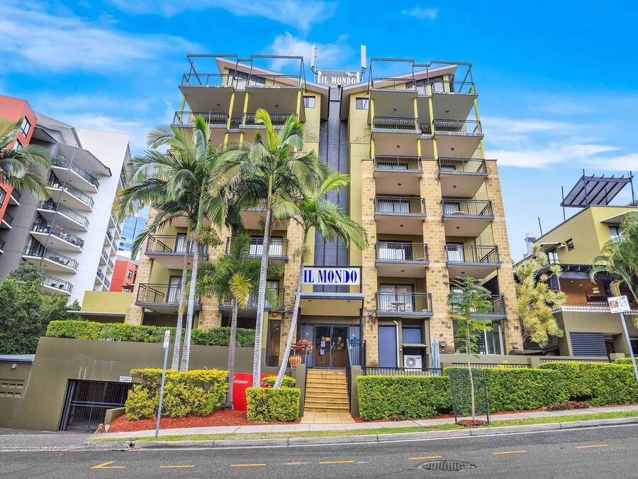 A multi-story building with balconies, a sign reading "IL MONDO," and palm trees in the foreground.