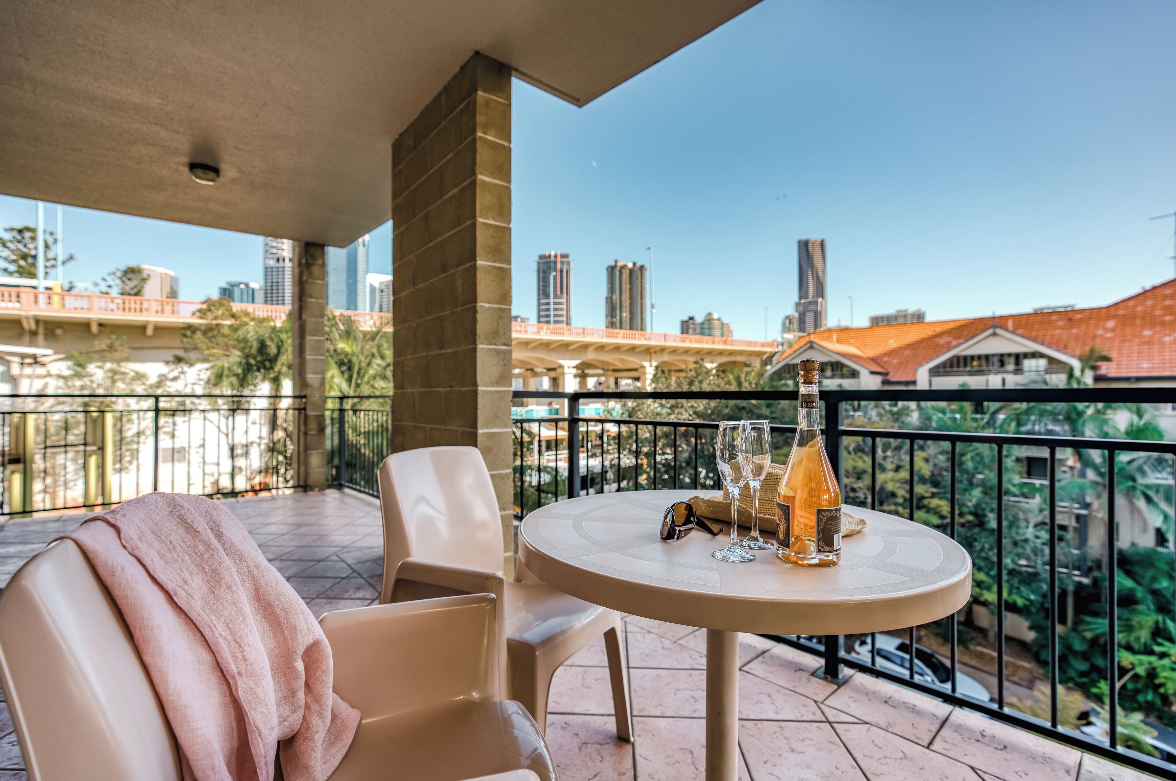 Un balcon avec une table, des chaises et une bouteille de vin.