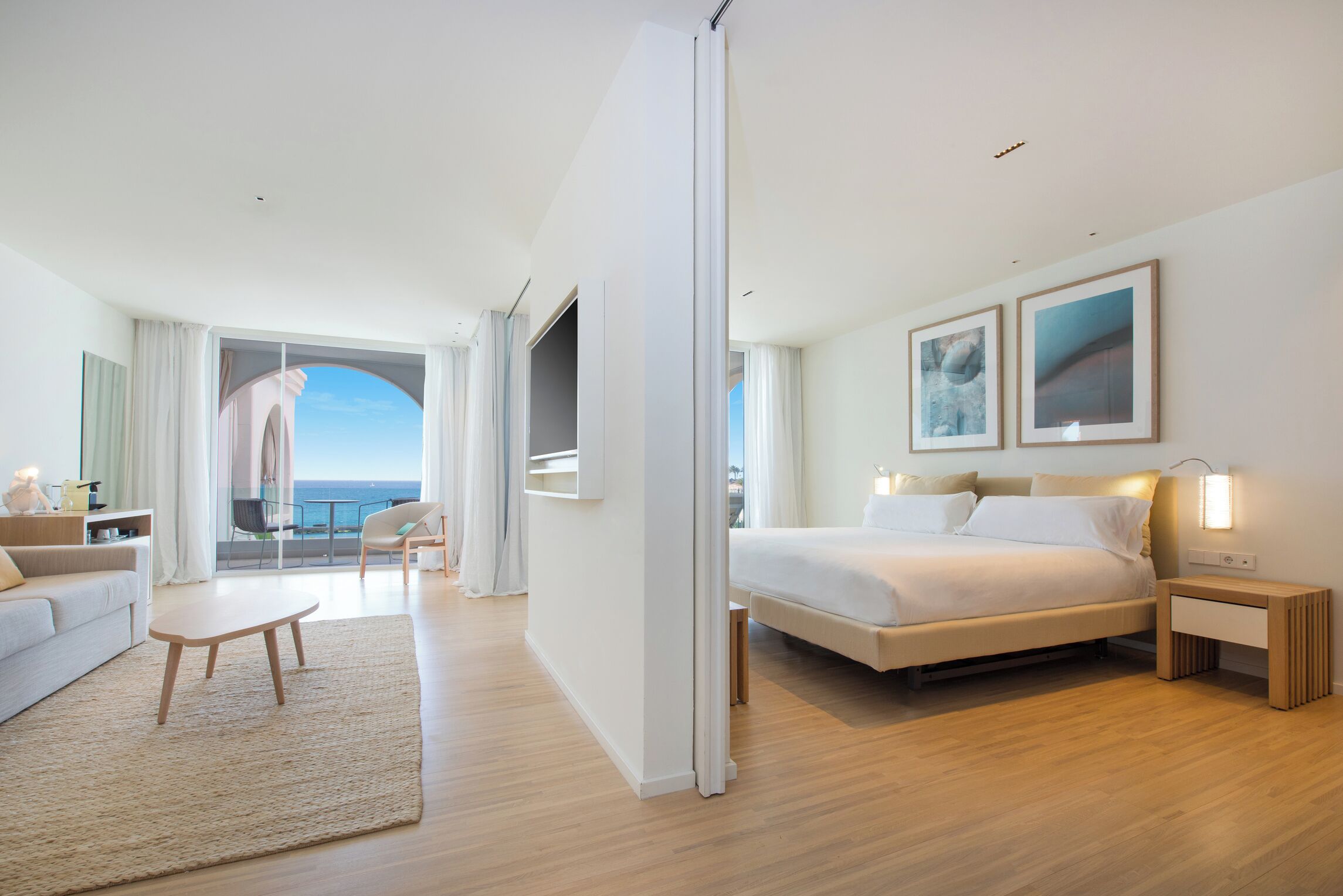 Una habitación de hotel moderna con una cama, mesita de noche y vistas al mar.