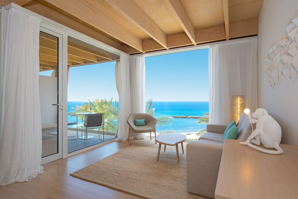 A spacious living room with a large sliding glass door leading to a balcony overlooking the ocean.