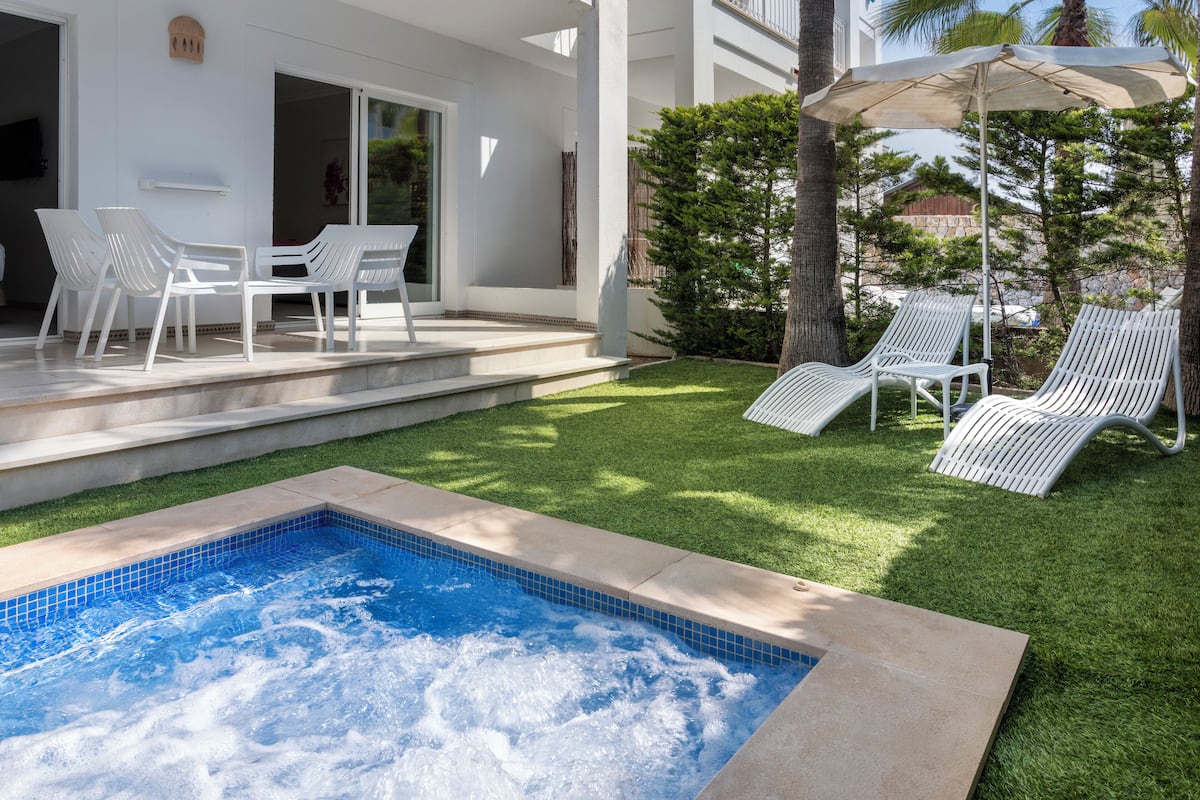 A swimming pool with a tiled edge, surrounded by a well-maintained lawn and white lounge chairs.