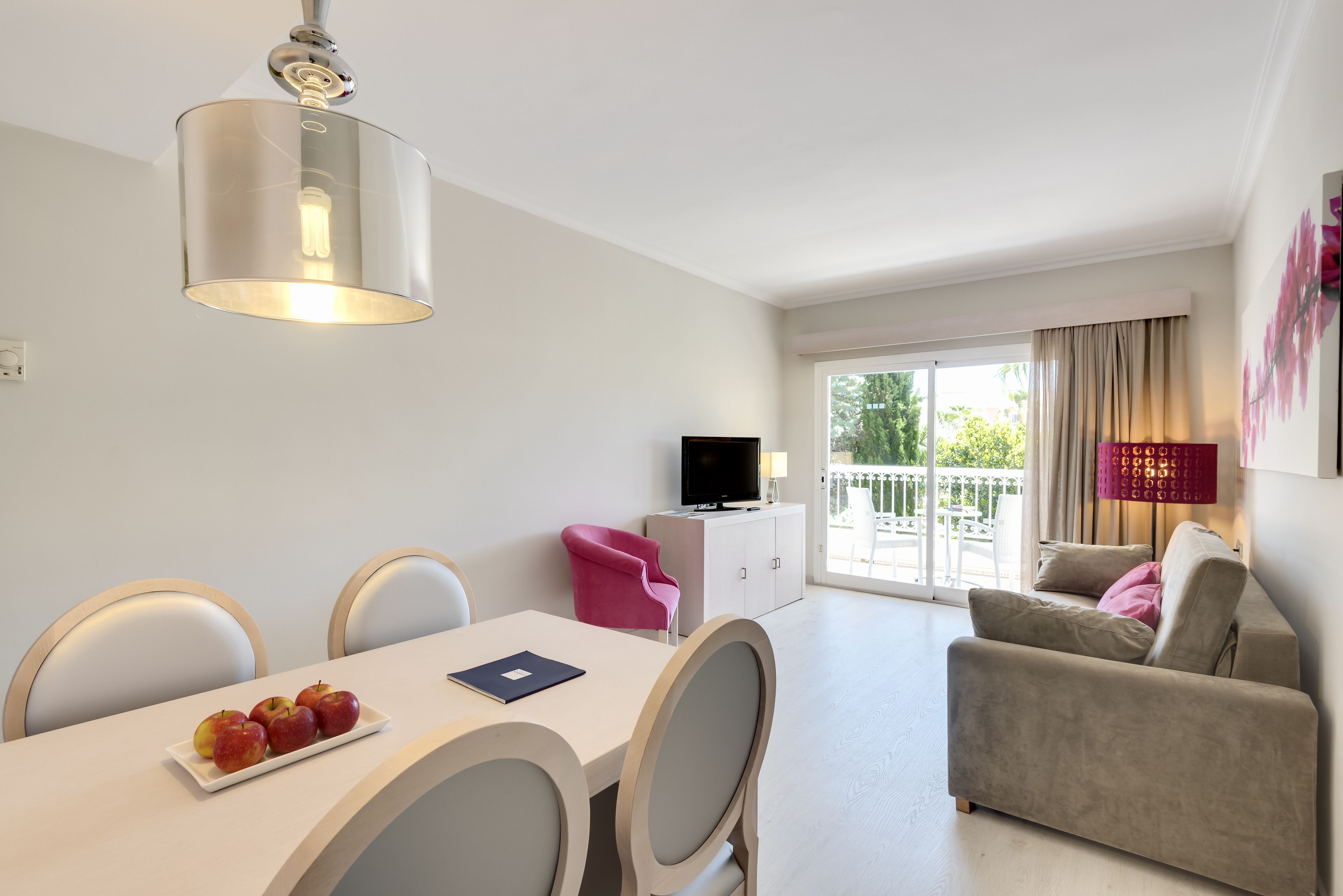 Ein modernes Wohnzimmer mit Essbereich, einer Couch, einem Fernseher und einem Balkon mit Blick.