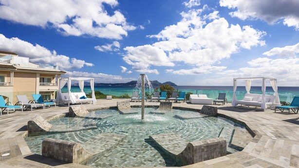 A pool area with clear water, lounge chairs, and a view of the ocean. - Playa Garden Selection Hotel & Spa (Muro)