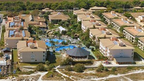 An aerial view of a coastal resort with beachfront villas, a swimming pool, and a sandy beach with sun loungers. - Playa Garden Selection Hotel & Spa (Muro)