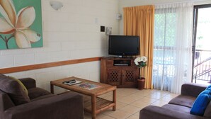 Una sala de estar con un sofá, una mesa de centro, un televisor y un cuadro en la pared.