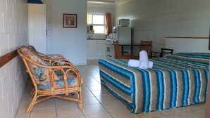 Una habitación con cama, una silla, escritorio, microondas y ventana.