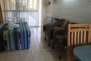 A room with a bed, a TV, wicker furniture, and a tiled floor. - Oasis Inn Cairns (Cairns North)