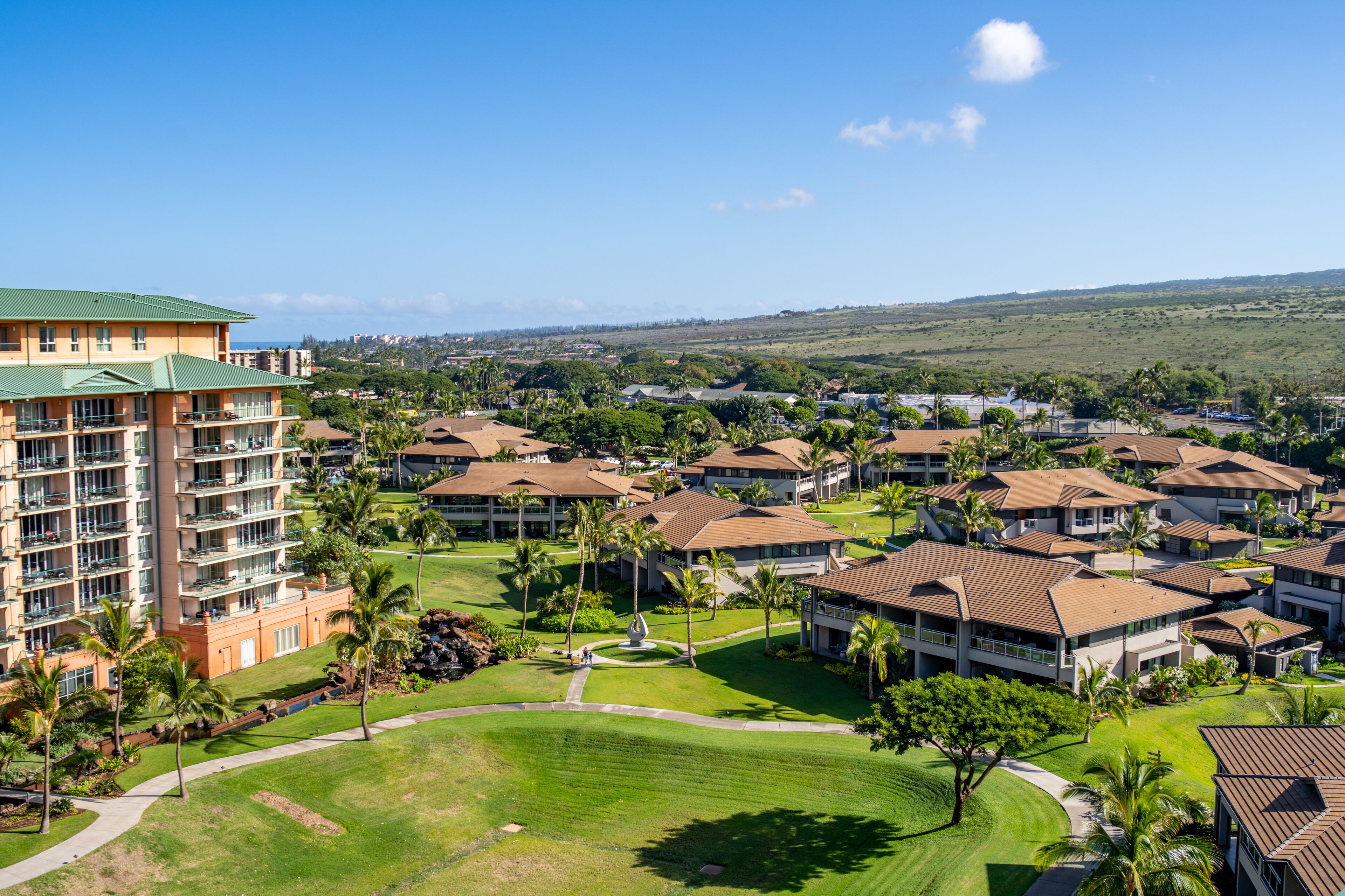 Un resort con varias construcciones, un césped central y follaje circundante.