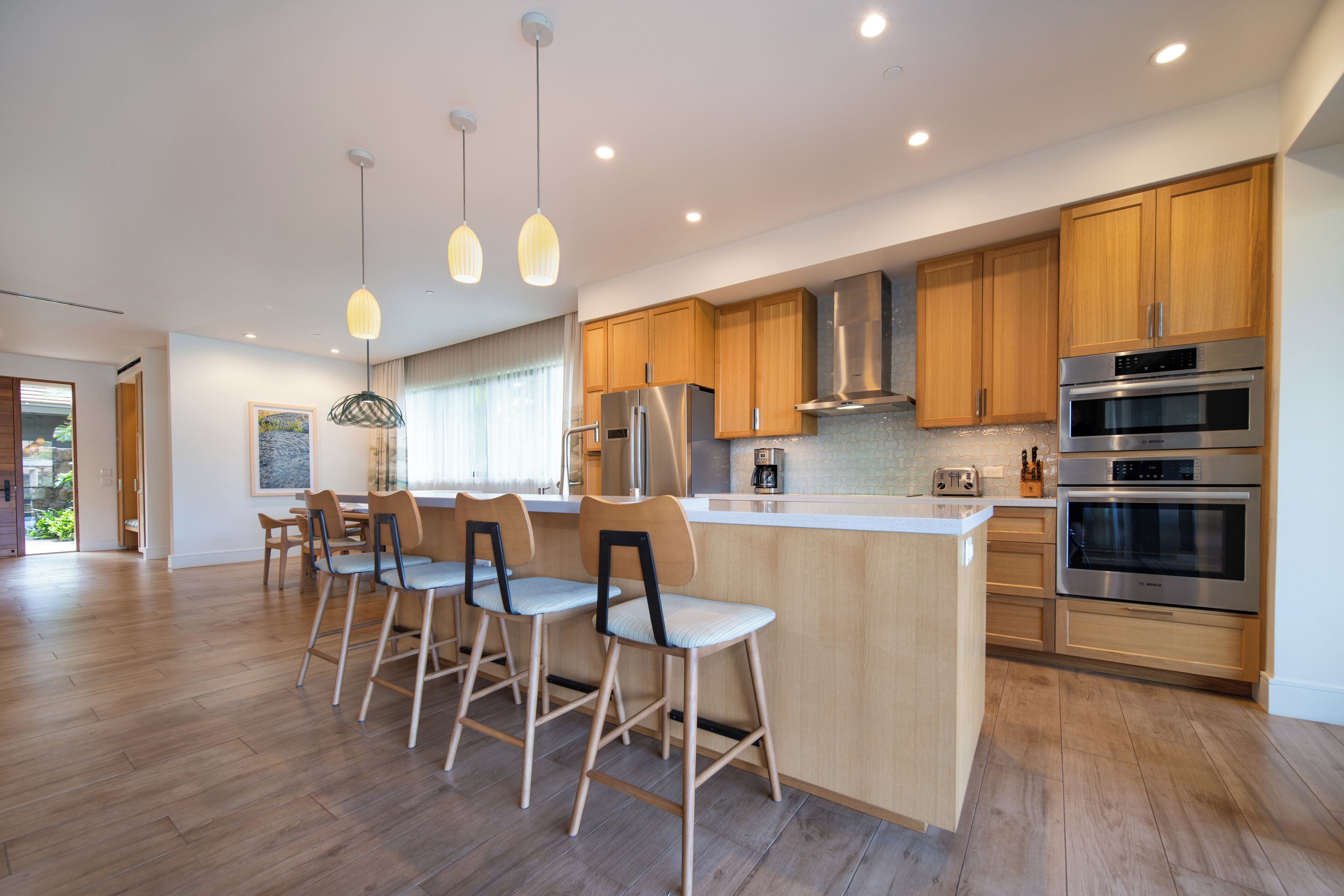 A modern kitchen with wooden cabinets, stainless steel appliances, and a central island with bar stools.