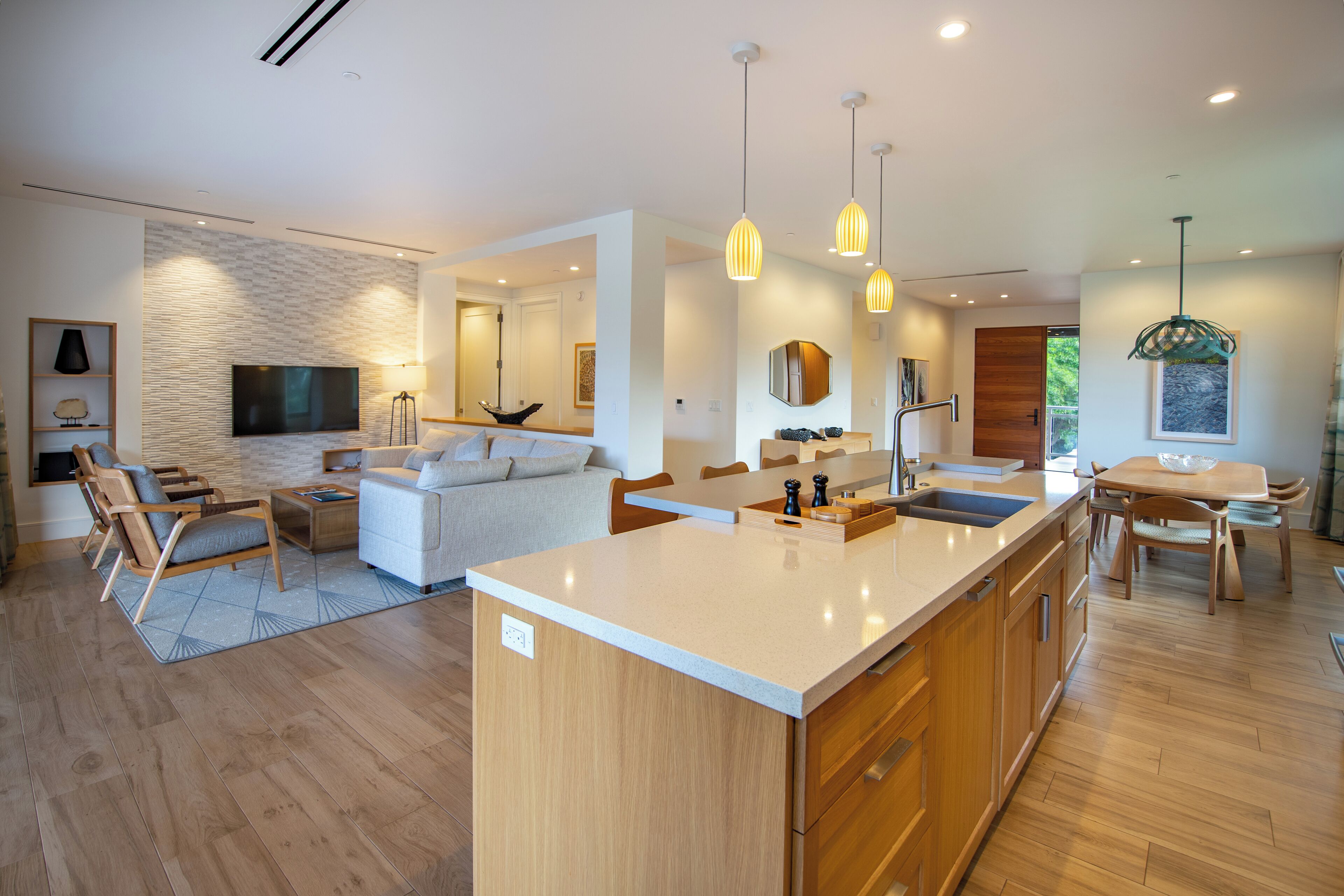 Une cuisine moderne dotée d’un îlot central, de meubles en bois et de luminaires suspendus.
