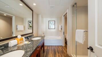 A modern bathroom with a double sink, a large mirror, a bathtub, and a glass shower enclosure.
